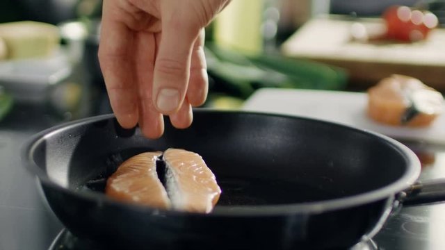 Close-up of Hands Putting Red Fish Fillet on a Hot Pan. Shot on RED EPIC-W 8K Helium Cinema Camera.