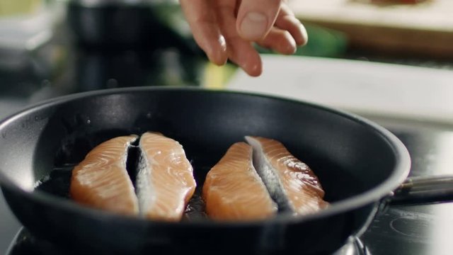 Close-up of Hands Putting Piece of Red Fish Fillet on a Hot Pan
