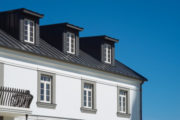 Top of residential house facade against blue sky