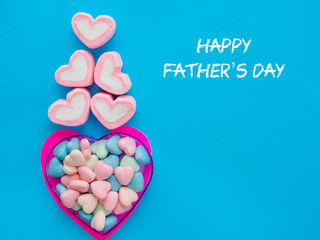 Father's day concept. Marshmallow in a heart frame with Happy father's day text on blue sky background
