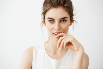 Portrait of young beautiful brunette girl looking at camera posing touching face over white background.