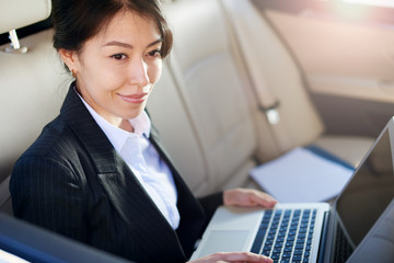 An attractive woman in a suit in the back seat of a car