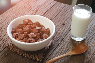 chocolate cereals with milk on wood table in morning light