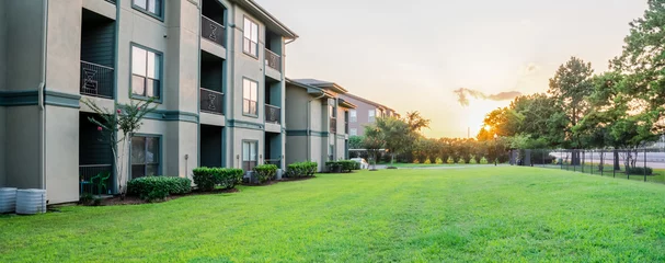 Foto op Plexiglas View from grassy backyard of a typical apartment complex building in suburban area at Humble, Texas, US. Sunset with warm light. Panorama style. © trongnguyen