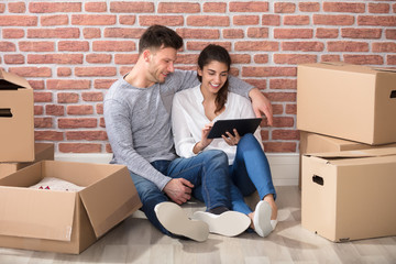 Couple Looking At Digital Tablet In Their New Home