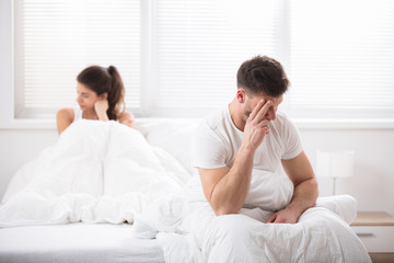 Worried Couple Sitting On Bed
