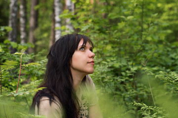 Portrait of a young girl in a forest park among green grass