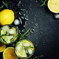 Summer cocktail with lemon, rosemary and ice, gray background, top view
