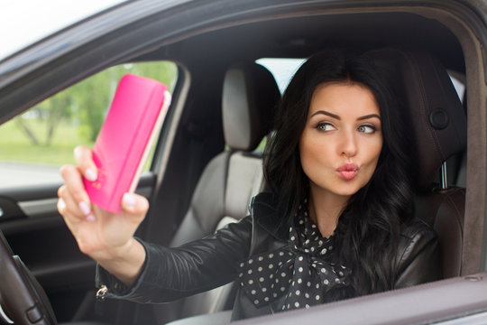 Beautiful brunette woman doing selfie in the car