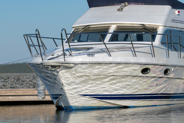 A white yacht is attached to the dock, and water is reflected on the boat hull