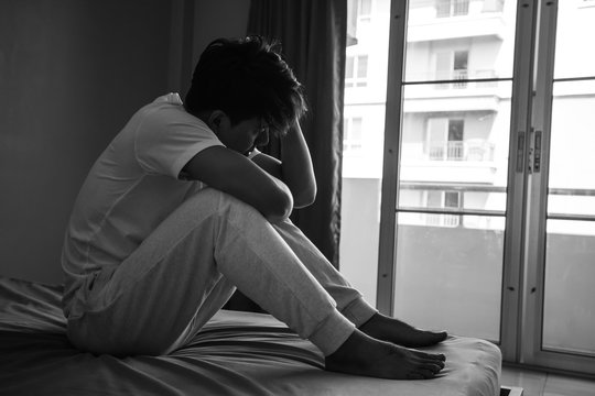 Asian man with sad mood in the room, sadness portrait concept, black and white tone.