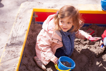 A little girl is playing in the sandbox