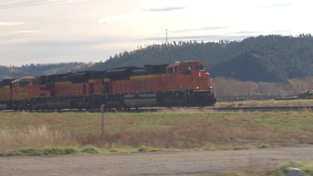 BILLINGS, MONTANA, CLOSE UP: Locomotive hauling freight train wagons loaded with coal along the hilly landscape across America. Train moving on railroad tracks transporting goods