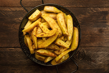 Crunchy roasted potatoes in skillet on dark rustic texture
