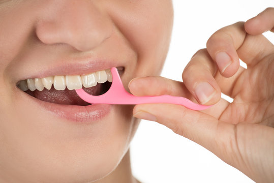Hygiene of the oral cavity. Young girl cleans teeth with floss, smiling and showing okay sign on a background.