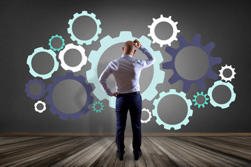 Businessman in front of a wall thinking about a cog wheel interface - business concept