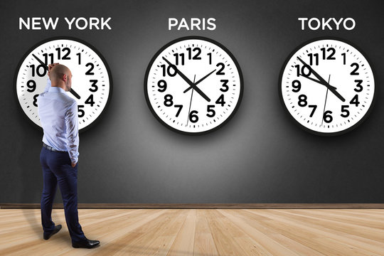 Businessman in front of a wallwith clocks of different country - Jetlag concept