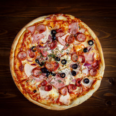 Delicious homemade pizza with mozzarella, ham, olives and fennel.