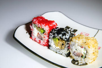 Three sushi on a white plate standing on the white glass 