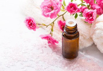 Essential oil, Mineral bath salts,  branch  of  small pink  rose  on the wooden table.