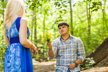 Young man giving a flower dandelion to girlfriend outdoors