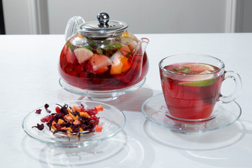 Red fruit and berry tea with raspberries in a glass teapot with mint isolated