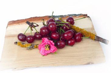 Close up fresh and appetizing cherries on a piece of wood isolated on the white background