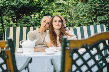 Middle Age Woman With Adult Daughter Talking And Relaxing In Garden