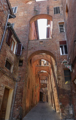 Narrow streets built of red bricks in medieval Siena. Characteristic is  large number of struts between buildings