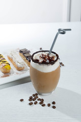 Ice coffee and coffee and nuts near desserts and macaroons in white background
