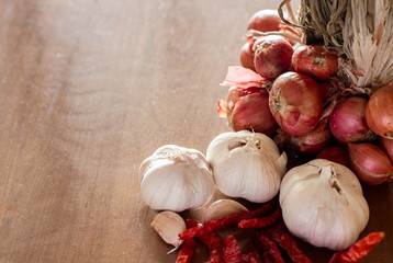 Garlic, shallots, dried chilies on wood background.