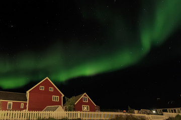 Northern lights and starlight sky over two red living houses, Nuuk, Greenland