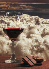 Red wine glass with chocolate and sunset cloudscape