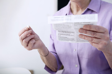Senior woman reading medication instruction sheet - obrazy, fototapety, plakaty