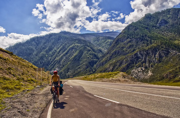 Obraz premium Chuiski road, Altai Republic. The road in the mountains, highway, paved road near the shore of the river Chuya. Sunny day in summer. Biking, cycling, cyclist.