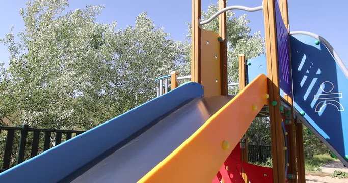 Three years old blonde child playing sliding in metal slide in outdoor playground, in public Park Valdebebas, Madrid Spain

