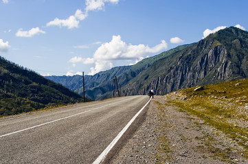 Fototapeta premium Chuiski road, Altai Republic. The road in the mountains, highway, paved road near the shore of the river Chuya. Sunny day in summer. Biking, cycling, cyclist.