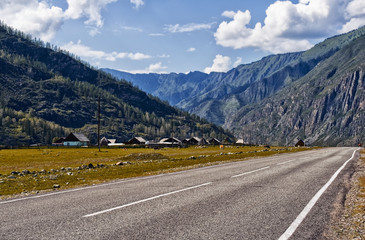 Chuiski road, Altai Republic. The road in the mountains, highway, paved road near the shore of the river Chuya. Sunny day in summer. Biking. Grass, herbs around.