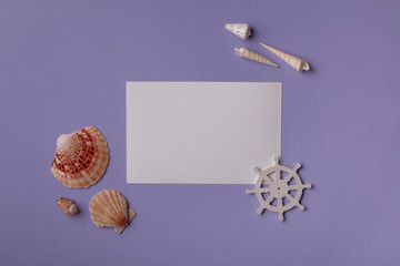 Summer background: From above shot of arrangement of paper card mockup, seashells and small steering wheel on purple. Top view. Flat lay.