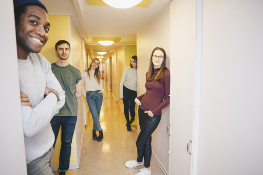 Young university students standing in dorm corridor