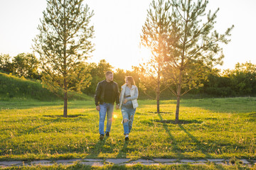 Pregnant woman with husband walking on meadow in the sunlight