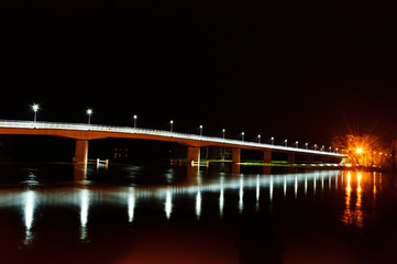 Most nad rzeka w nocy oświetlony latarniami.