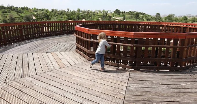 Three years old blonde child playing running on wooden tower, in public Park Valdebebas, Madrid Spain
