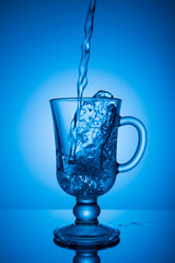 Sparkling water. Dynamic spike, thirst quenching on a hot day. Clear water on a blue background.
