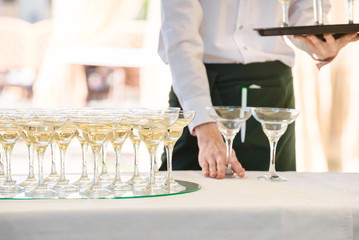 Man waiter hold glasses and serving table outdoor