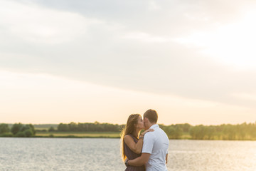 Young couple in love outdoors embracing and laughing together at lake