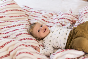 Cute little boy at home lying on bed smiling.