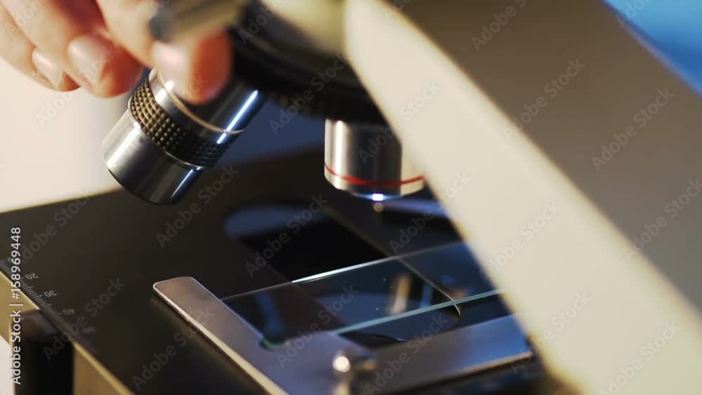 Poster researchers working in lab with microscope, close up