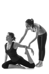 Trainer helping woman with positioning on her yoga pose.