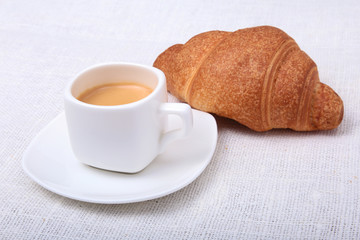 Crispy homemade fresh croissants and cup of coffee espresso on a white background, morning breakfast, selective focus